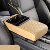 A tan car center console armrest cushion with a black cup holder is shown in a gray and black car interior.