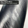 Close-up texture of faux wood effect film showing embossed wood grain in a dark gray finish.