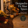 A black cat and pumpkin garden stake light shaped like a crescent moon, illuminating a pathway.