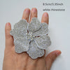 A hand holds a white rhinestone flower sew-on patch, measuring 8.5cm or 3.35 inches.