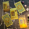 A collection of gold foil tarot cards and a guidebook laid out on a dark surface.