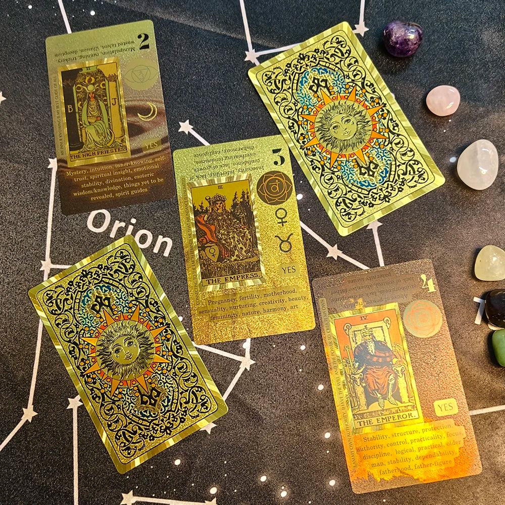 A collection of gold foil tarot cards and a guidebook laid out on a dark surface.
