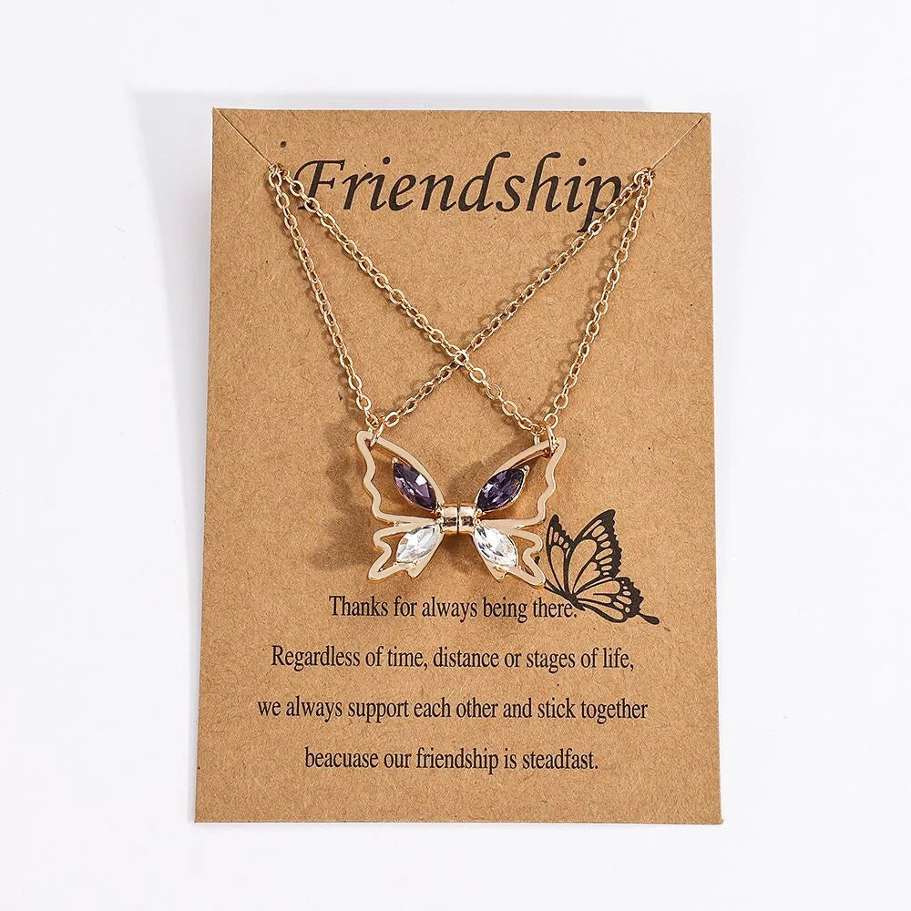 A delicate gold chain necklace featuring a purple crystal butterfly pendant, presented on kraft paper.