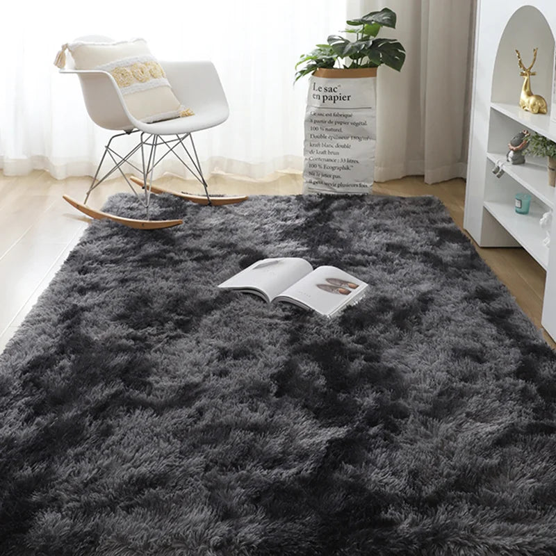 A dark gray Nordic furry accent rug placed on a wooden floor with a white chair and potted plant in the background.