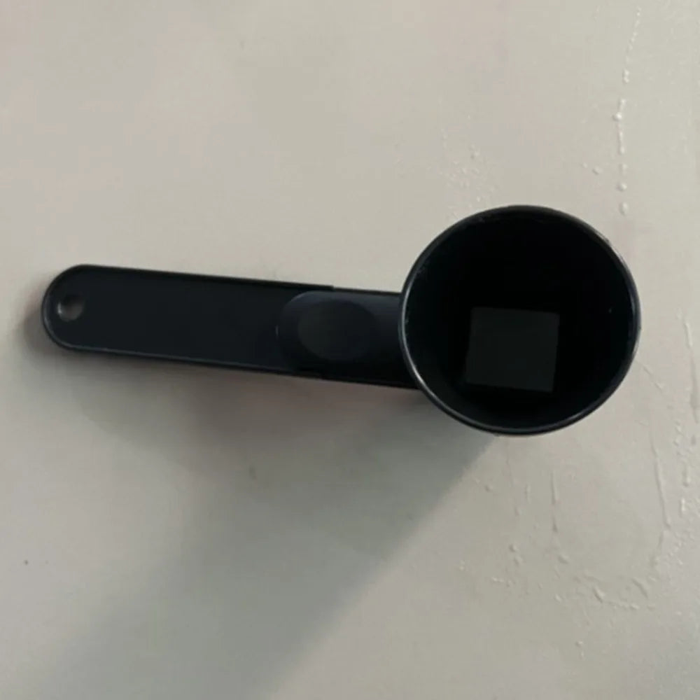 A black 2-in-1 sliding coffee scoop and funnel attached to a white surface.