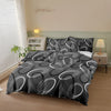 A black and white geometric print duvet cover set with pillows displayed on a bed in a light-colored room.