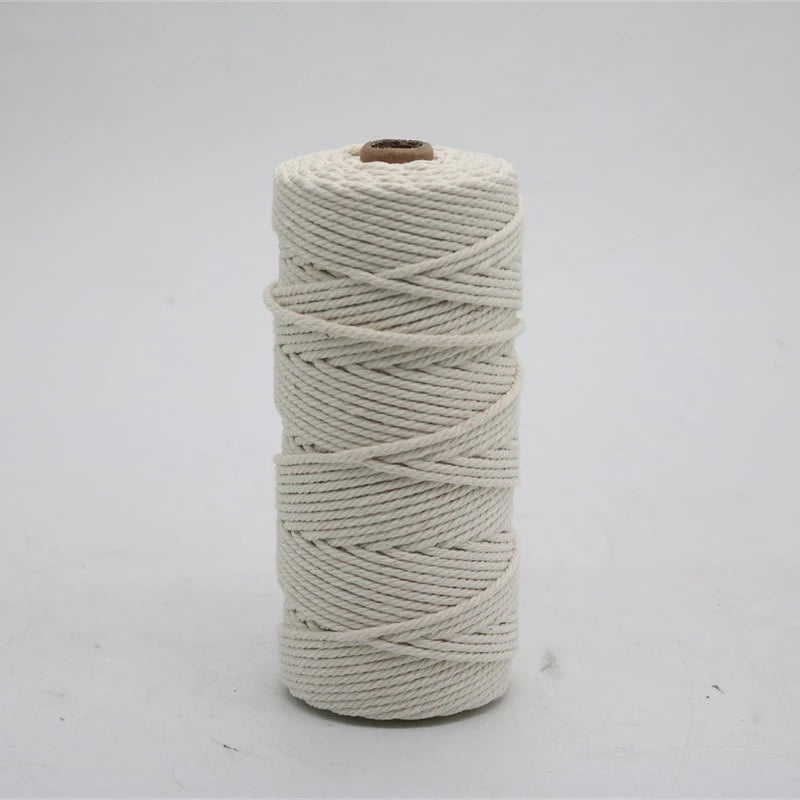 A spool of cream-colored macrame cord, made of 100% cotton, used for crafting.