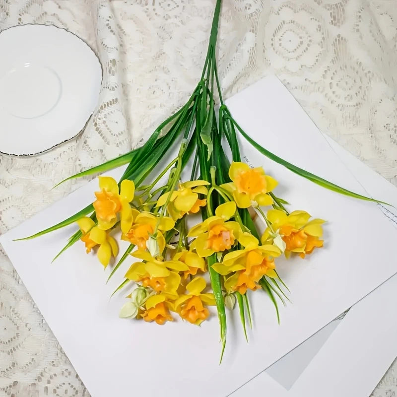 A bouquet of realistic artificial yellow and orange daffodil flowers displayed on white paper.