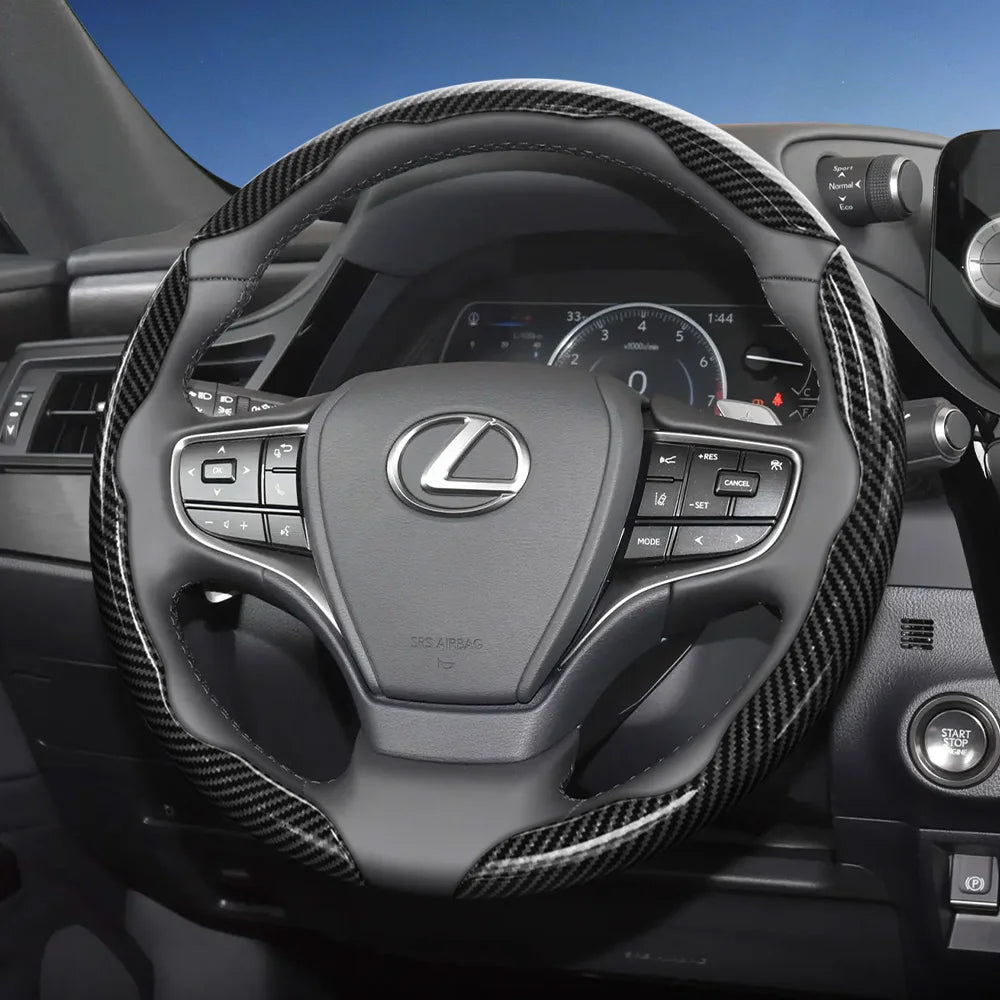 A close-up view of a black steering wheel with carbon fiber texture grips and controls inside a car