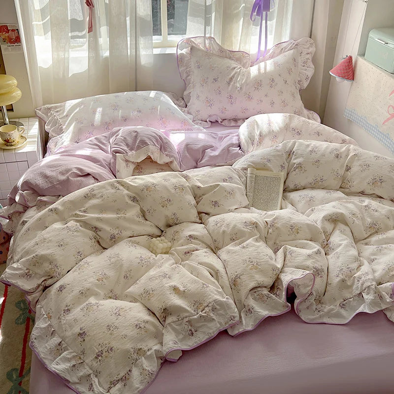 A floral duvet cover set with pillowcases and a flat sheet in light pink and cream tones on a bed.