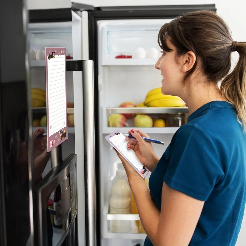 A woman in a blue shirt is writing on a magnetic dachshund shaped to-do list notepad inside a refrigerator.