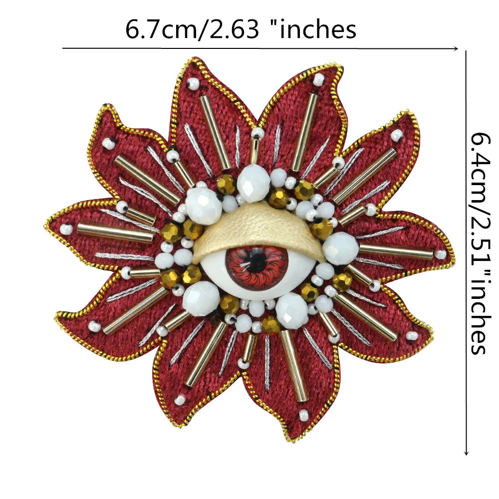 A large, reddish-brown floral patch featuring a gold eye design with white and brown beads and rhinestones.