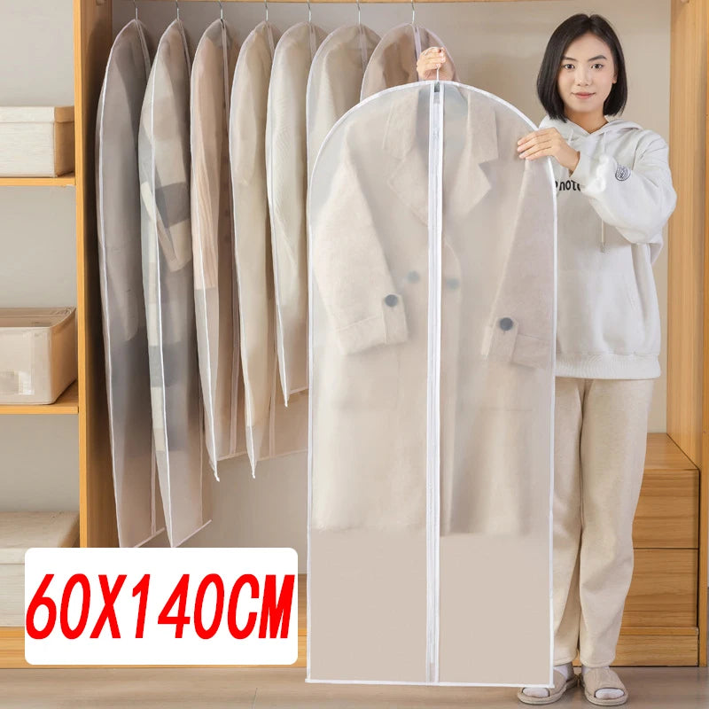 A woman stands next to a transparent zippered garment bag displaying several light-colored coats and jackets on a wooden rack
