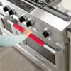 A hand is gripping a red velvet handle cover on a silver kitchen appliance, likely a stove or oven.