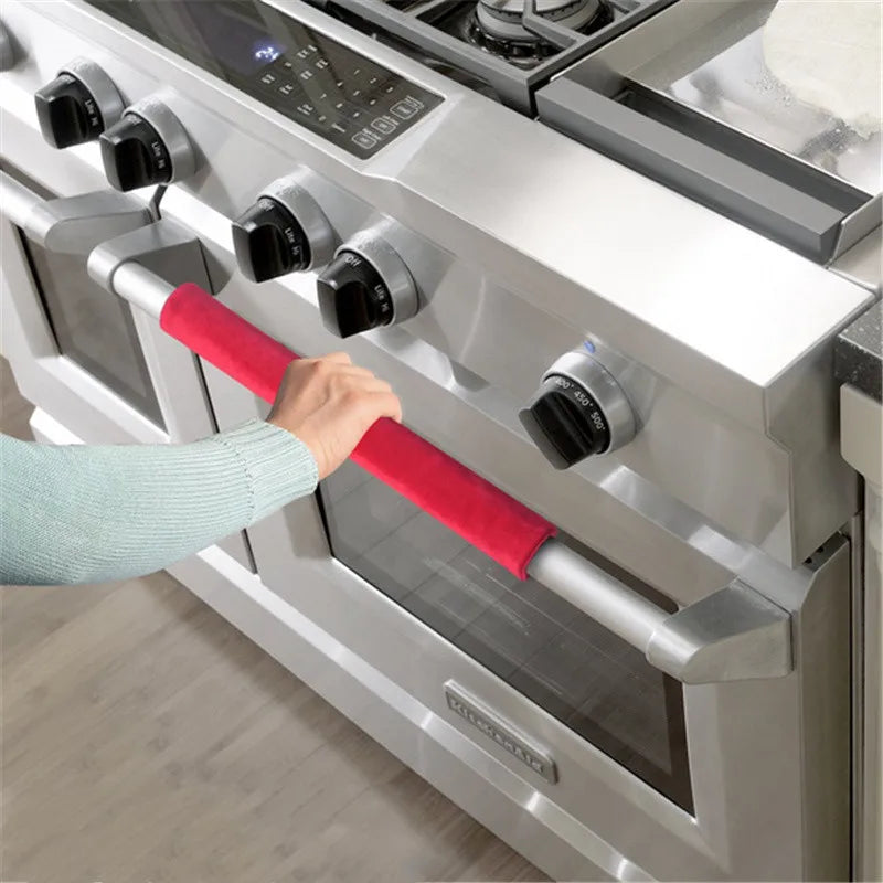 A hand is gripping a red velvet handle cover on a silver kitchen appliance, likely a stove or oven.
