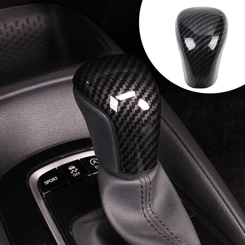 Close-up of a black carbon fiber gear shift knob cover for a Toyota Camry or Corolla.