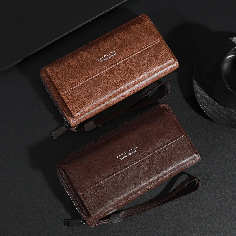 Portefeuille pochette en cuir marron avec fermeture éclair et sangle sur une surface sombre.