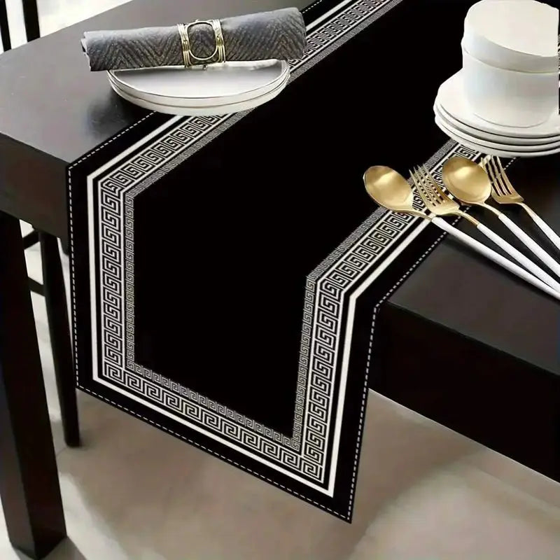 Black geometric table runner and placemat set with gold accents and a gray napkin roll.