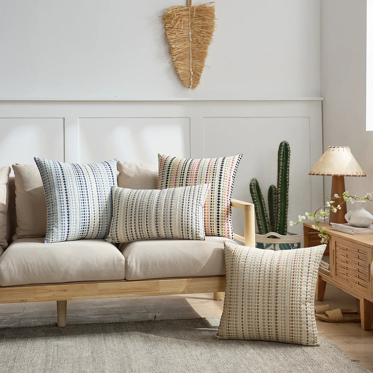 A set of two bohemian linen pillow covers in muted tones displayed on a light-colored sofa.