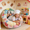 A young girl is sitting in an inflatable plush toy storage bag surrounded by kitchen decor and toys.