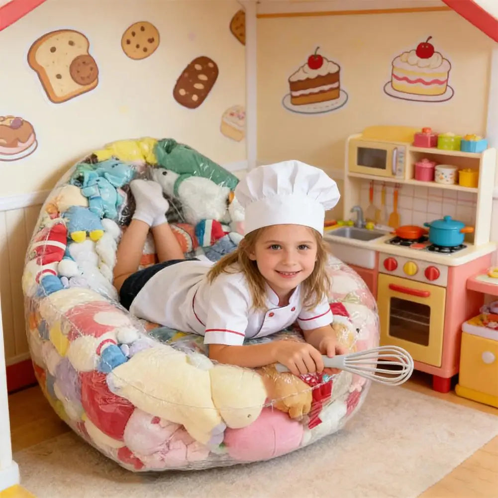 A young girl is sitting in an inflatable plush toy storage bag surrounded by kitchen decor and toys.