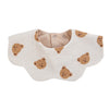 A light beige muslin cotton baby bib with a bear pattern and adjustable snap closure.