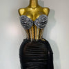 A gold mannequin displays a sparkly two-piece party outfit with a sheer top and a black draped skirt.