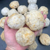 A hand holds a cluster of natural agate geode crystals.