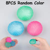 Eight colorful, soft textured stress balls in various shades are displayed on a gray surface and held by hands.