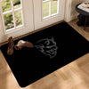 A black anti-slip doormat featuring a silver stylized animal head design placed on a wooden floor.