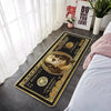 A rectangular gold and black banknote pattern anti-slip floor mat placed on a gray floor next to a white bed.