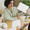 A woman is writing on a poster showing a double-sided fraction number line for classroom math learning.