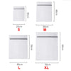A set of fine mesh laundry bags in white for various sizes S, M, L, and XL.