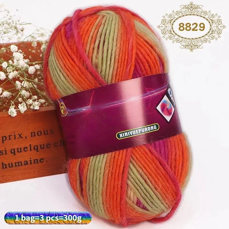 A ball of gradient dyed orange and green wool blend yarn with a purple label and a decorative stamp.