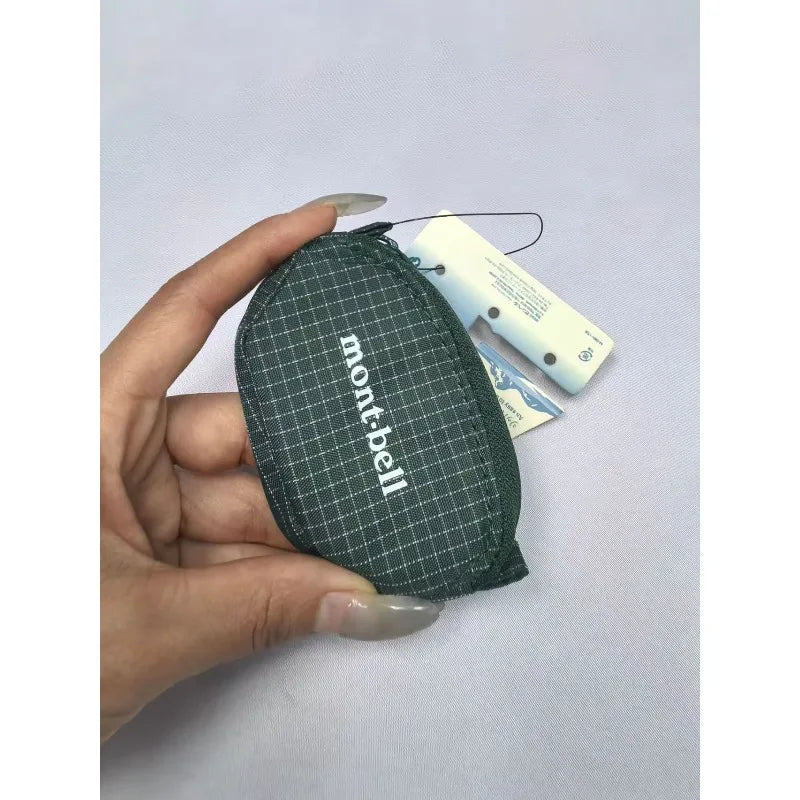 Une main tient un étui de casque en nylon à carreaux vert foncé avec une étiquette.