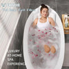 A woman relaxing in a white bath pillow filled with pink bath salts and bubbles for a luxury at-home spa experience.