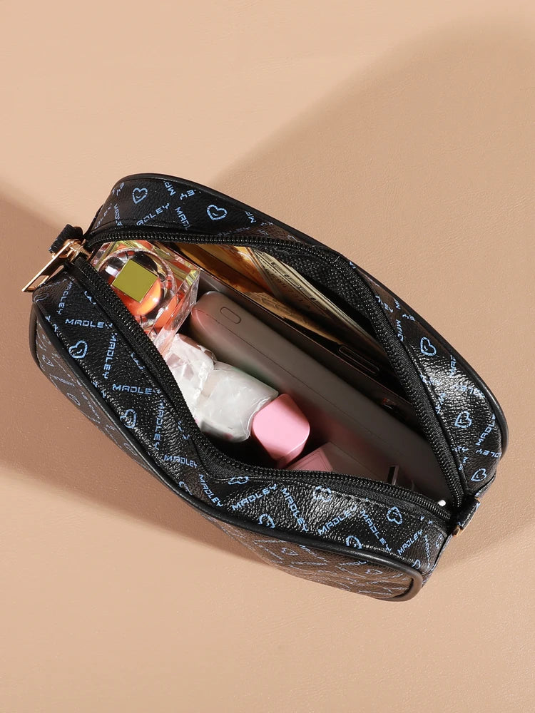 A black patterned compact crossbody bag is shown open, revealing a smartphone and perfume bottle inside.