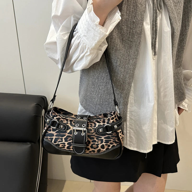 A close-up of a leopard print PU leather shoulder bag carried by a person wearing a white shirt and gray cardigan.