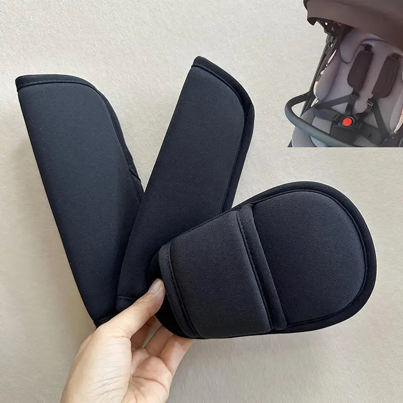 Black fabric cushion covers for baby stroller and car seat belts being held by a hand
