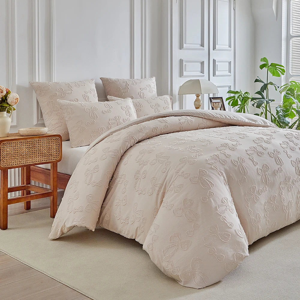 A beige duvet cover set with a subtle leaf print pattern displayed on a bed in a bright room.