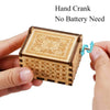 A hand cranked wooden music box made of light wood with intricate patterns.