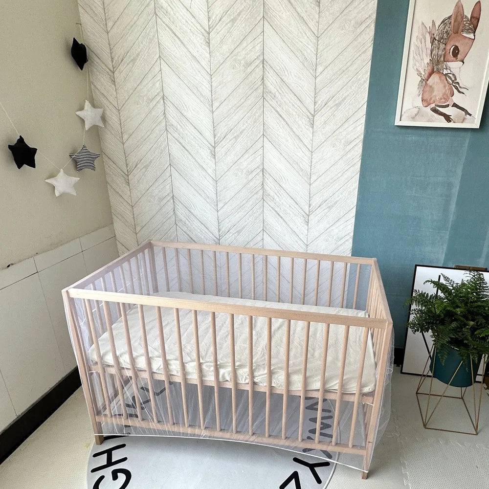 A light wood breathable mosquito net crib for a baby, set against a pale wall.