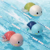 Three wind-up swimming turtle bath toys in green, white, and blue floating in clear water.