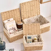 A natural woven rattan storage basket filled with small items like a book, jar, and a small electronic device.