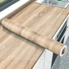 A roll of self-adhesive wood grain wallpaper is displayed on a light wooden countertop.