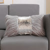 A decorative pillow featuring silver and gold sequin fabric surrounded by soft gray faux fur on a sofa.