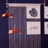 A sheer pink beaded string curtain hangs vertically against a dark blue background.
