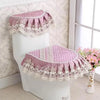 A pink lace toilet seat cover set with a ruffled cushion placed on a white toilet.