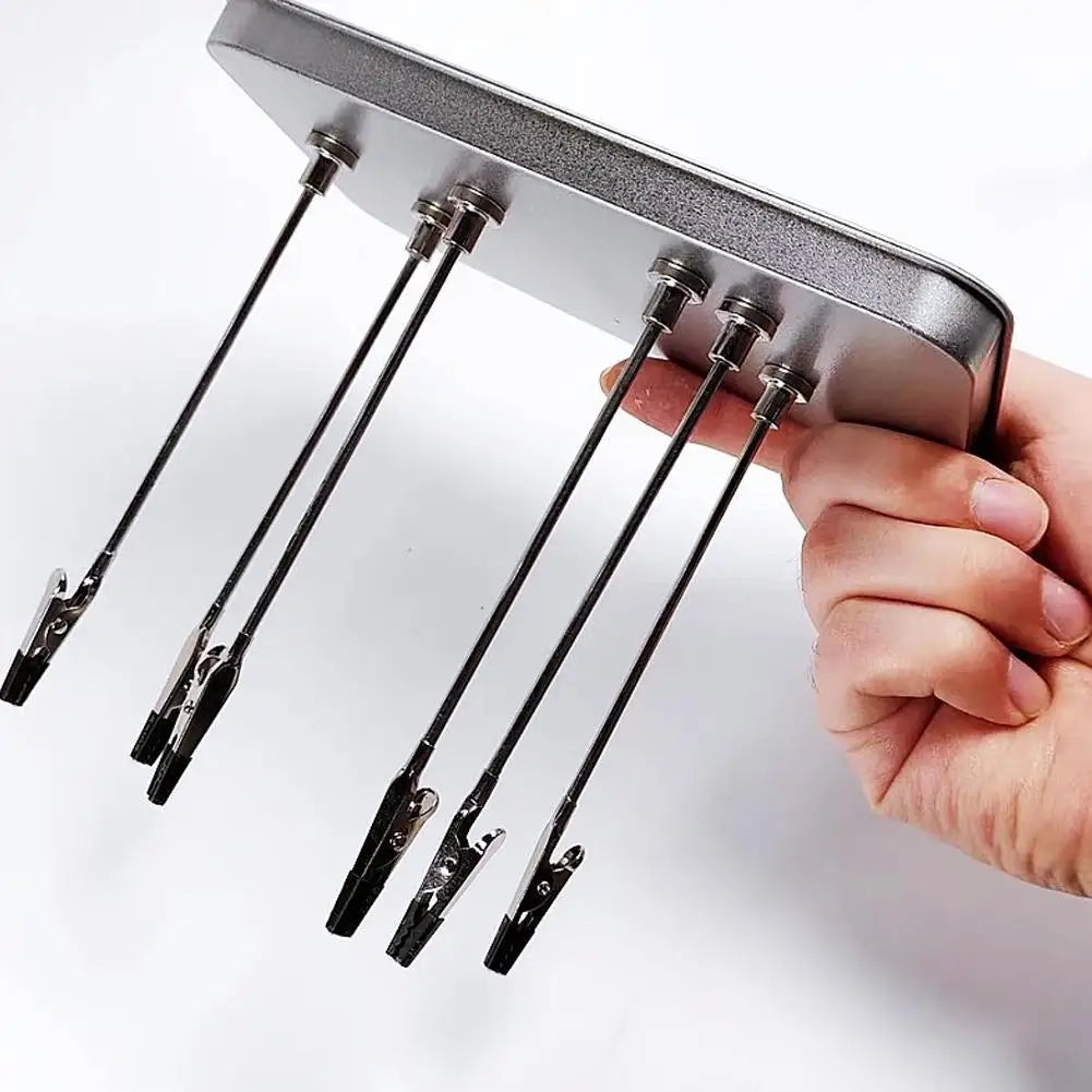 A hand holds a magnetic helping hands tool with flexible gooseneck arms and alligator clips.