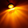 A bright LED side marker light shining a strong, warm yellow beam across a dark surface.